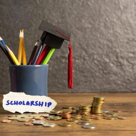 Education and back to school concept with graduation cap on pencils colour in a pencil case on dark background / scholarships with money coin wooden table