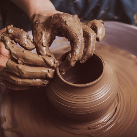 Woman hands working on pottery wheel and making a pot.